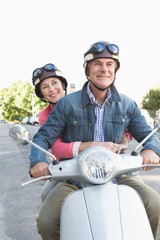 Naklejka premium Happy senior couple riding a moped