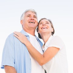 Happy casual couple embracing under blue sky