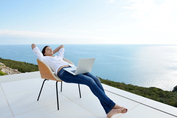 relaxed young woman at home working on laptop