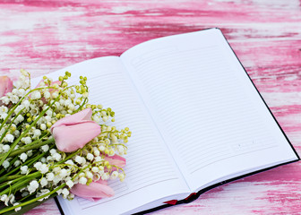 notebook and a bouquet of lilies of valley and tulips