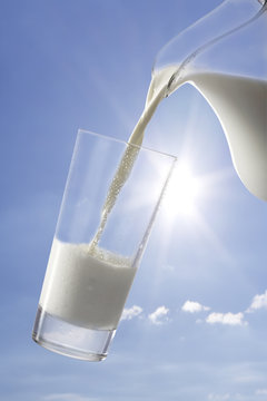 Milch aus Krug ins Glass gießen, Sommerhimmel, Außenaufnahme