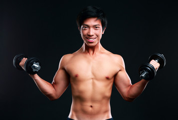 Fototapeta na wymiar Happy asian man working out with dumbbells on black backgroung