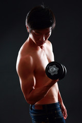Fototapeta na wymiar Asian man working out with dumbbell on black background