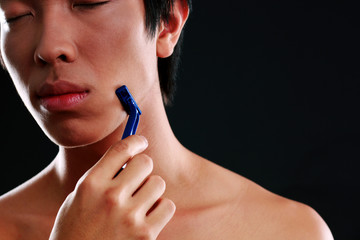 Asian man shaving on black background