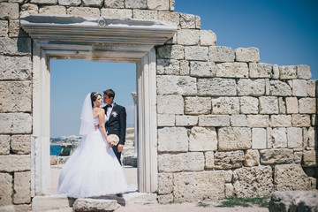 Happy bride and groom posing on the background of  ancient ruins