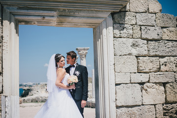 Happy bride and groom posing on the background of  ancient ruins