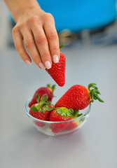 Closeup on young woman taking strawberry