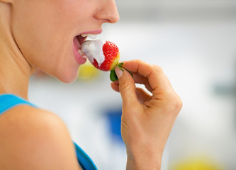 Closeup on young woman eating strawberry