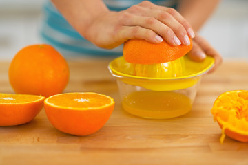 Closeup on young woman making fresh orange juice