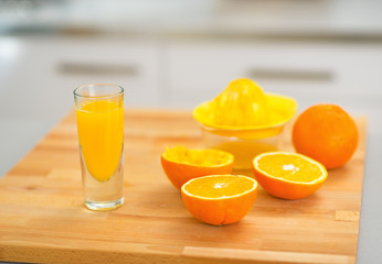 Closeup on glass of fresh orange juice and oranges on table
