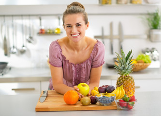 Portrait of young housewife with fruits in modern kitchen