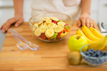 Closeup on young housewife making fresh fruit salad