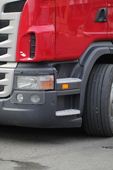 Close-up of a large red truck with headlights and bumper