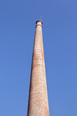 Old brick chimney against blue sky
