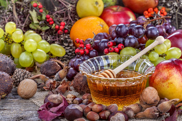 Autumn fruits, nuts and vegetables with honey on the table