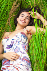 Fototapeta premium Young woman resting and day lying down on green grass