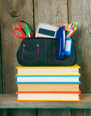 Books and school tools on a wooden shelf.