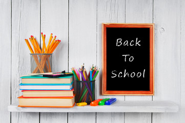 Books and school tools on wooden shelf.