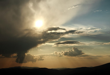 The sky in the rays of the sun at sunset in mountains