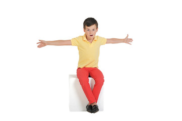 Fototapeta na wymiar the boy is 7 years old sitting on the cube in the yellow shirt a