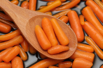 Canned baby carrots in a wooden spoon