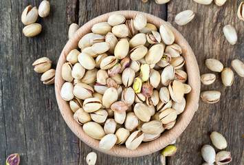full bowl of pistachio on wooden surface
