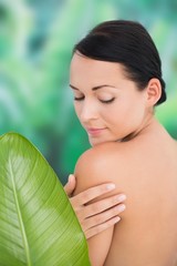 Beautiful nude brunette posing with green leaves