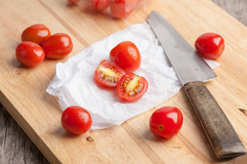 Red small tomatoes on wood board.