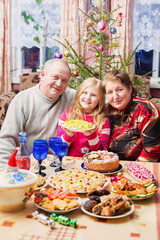 grandparents with little girl  sitting at festive table