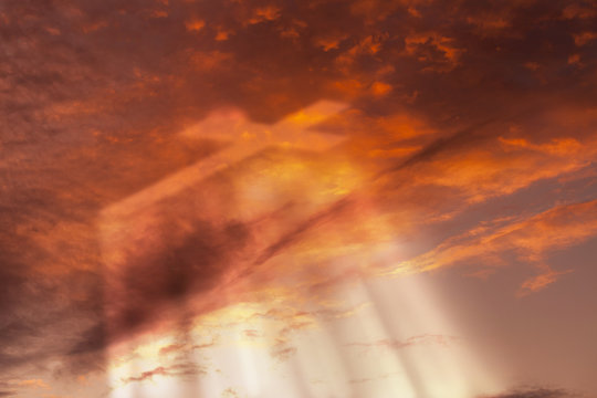 Cross appears in the sunset sky with rays of light