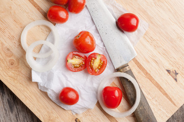Red small tomatoes on wood board.