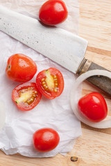 Red small tomatoes on wood board.