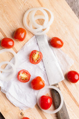 Red small tomatoes on wood board.