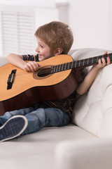Smiling caucasian boy is playing the acoustic guitar.