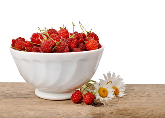 Ripe raspberries in a bowl on a wooden table on a white backgrou