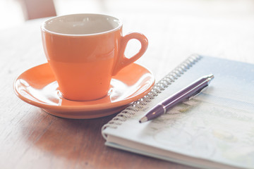 Cup of coffee with pen and spiral notebook