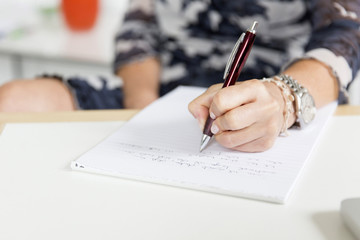 Hand (Frau) schreibend mit Kugelschreiber und Notizblock