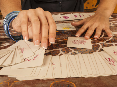 Manos de mujer con cartas de Tarot sobre una mesa. Vista de frente y de cerca