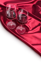 Two wine glasses with red wine on the red silk