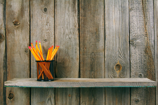 Pencils on a wooden shelf.