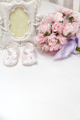 Obraz na płótnie Canvas Flowers, photoframe and children's sandals on the bed
