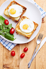 Croque monsieur with eggs and salad on vintage table
