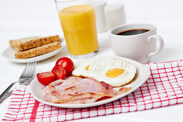 Breakfast with fried eggs and bacon on white table wide view