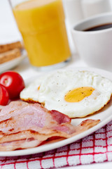 Breakfast with fried eggs and bacon on white table closeup