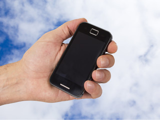 mobile and hand with sky background