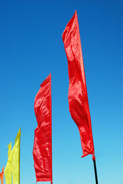 Red and yellow flags wave. Blue sky background. Taken in Moscow.