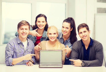 smiling students pointing to blank lapotop screen