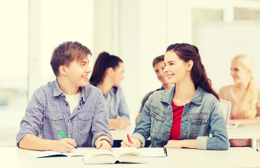 two teenagers with notebooks and book at school