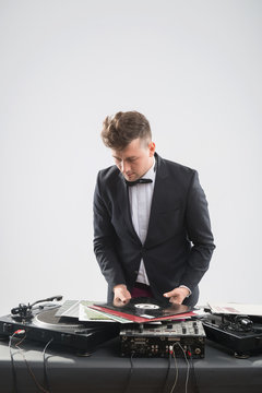 DJ In Tuxedo Looking At His Vinyl Records Standing By Turntable