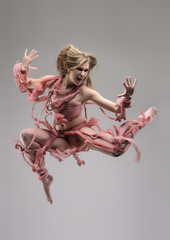 Jumping swathed woman in studio over gray background